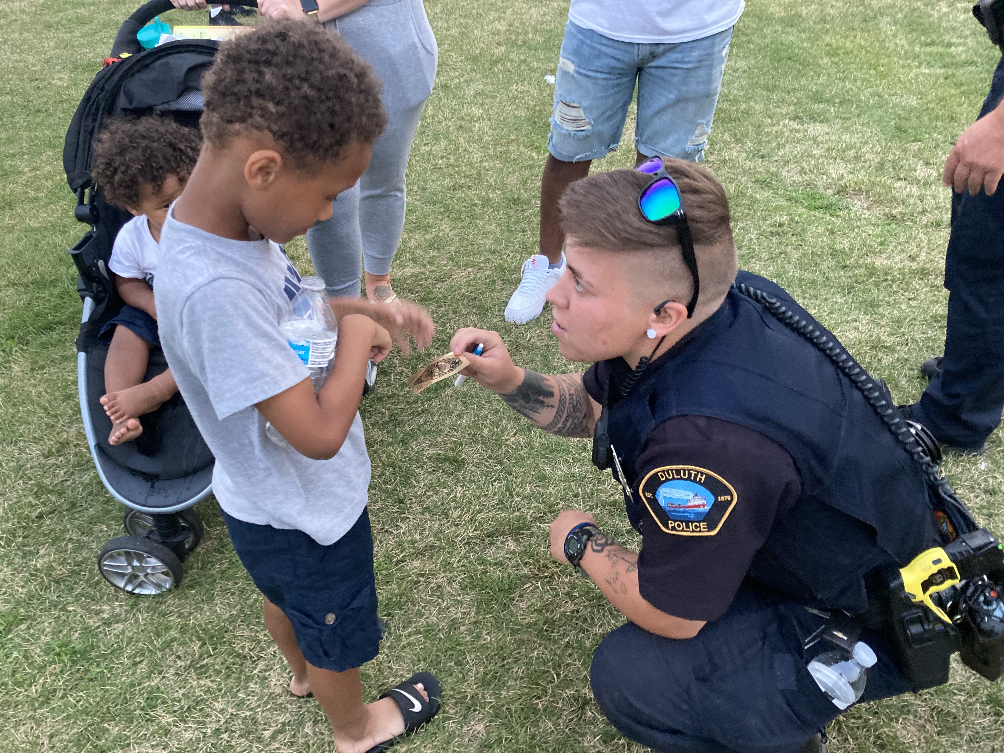 Officer Kaylee McMillen interacts with a child in our community by handing him a 'Junior Officer' sticker.