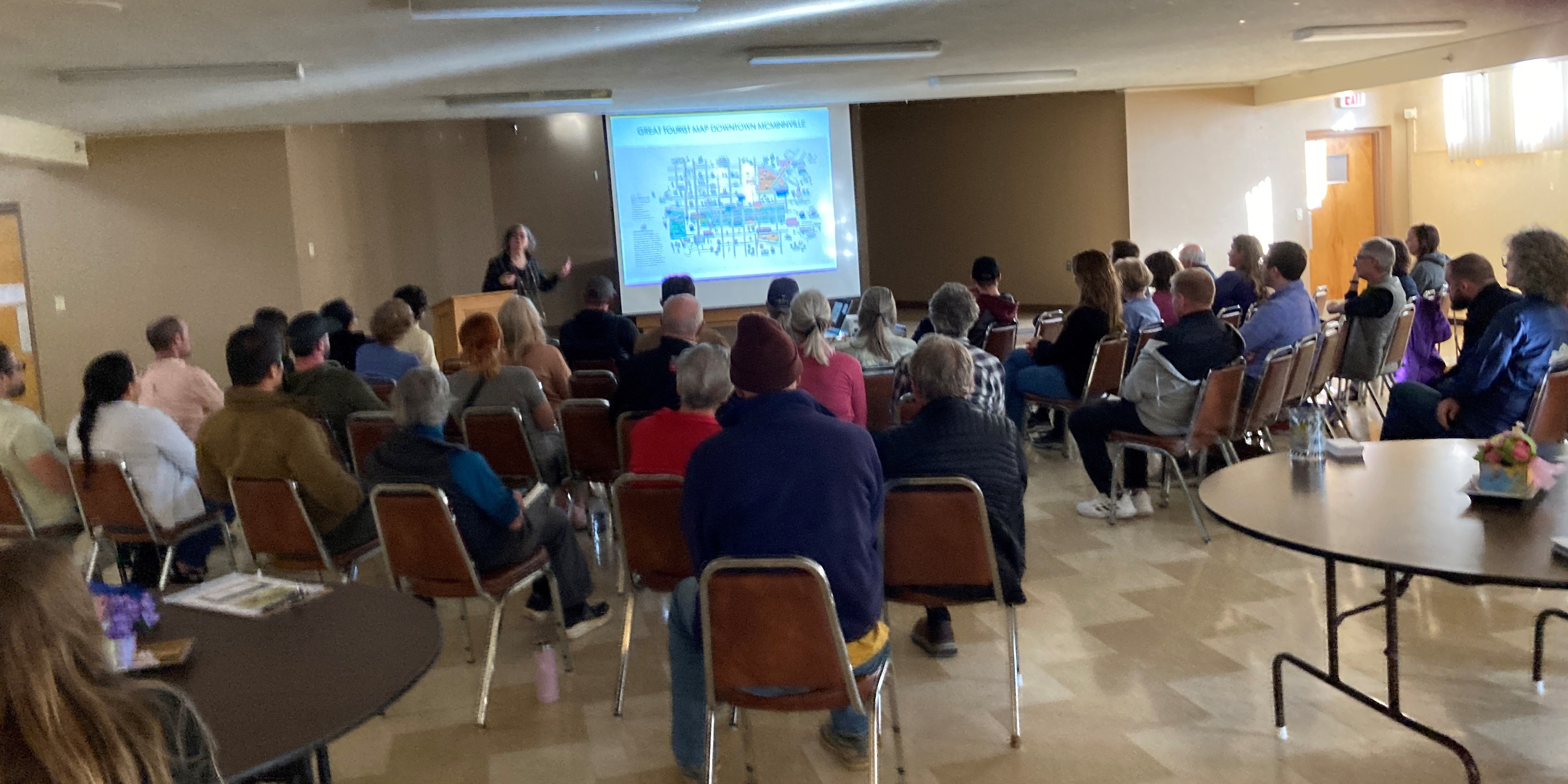 A photo from the May 5, 2025, Building Blocks meeting showing the presenter describing a slide for a group of 30 people.