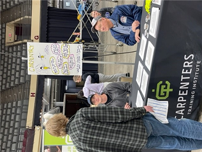 Students visit a table staffed by carpenters at event